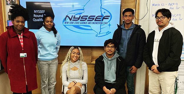 People smiling at the camera and standing next to a sign that says NYSSEF