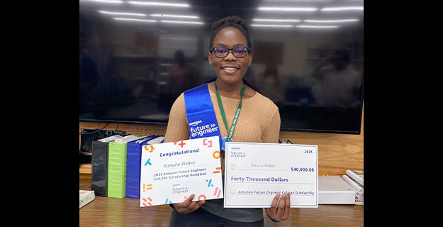 Kimone Walker smiling while holding a large check and an award