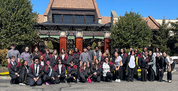 People wearing robes and gathered outside smiling at the camera
