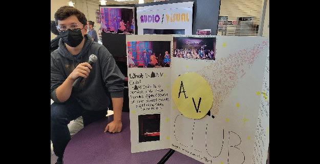 Student sitting next to his AV Club Poster