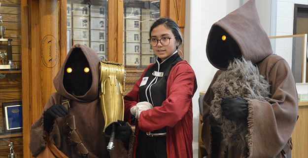 Two people dressed up as Jawas while a third person poses for the camera