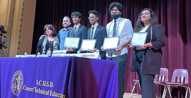 Students on Stage Holding Awards