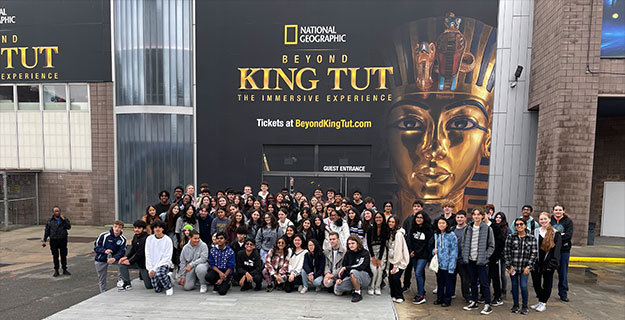 A large group of people around a sign that says Beyond King Tut