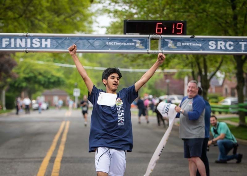 Student with arms raised as they cross the finish line
