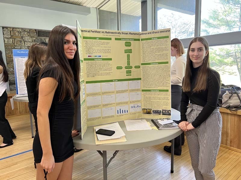 Two students stand next to a research project