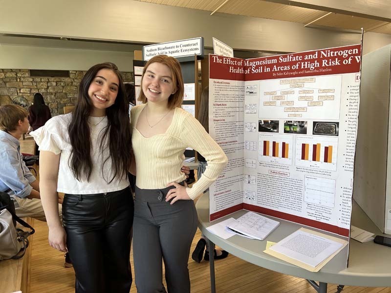Two students stand next to a research project