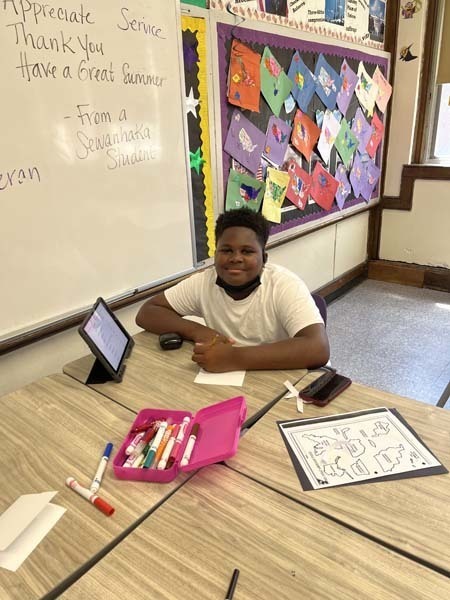 Student smiling at the camera while sitting at their desk
