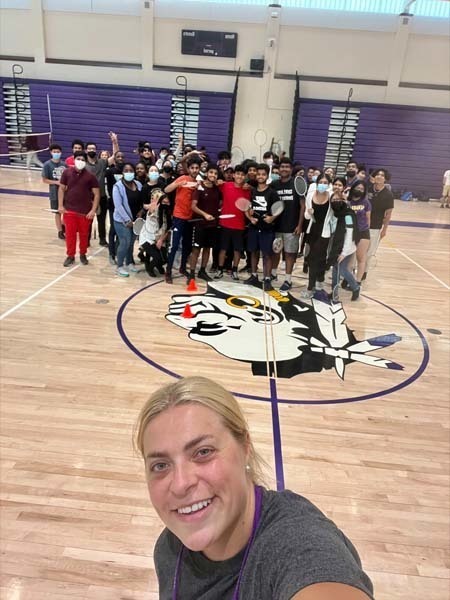 Coach taking a selfie with the badmitton team behind them