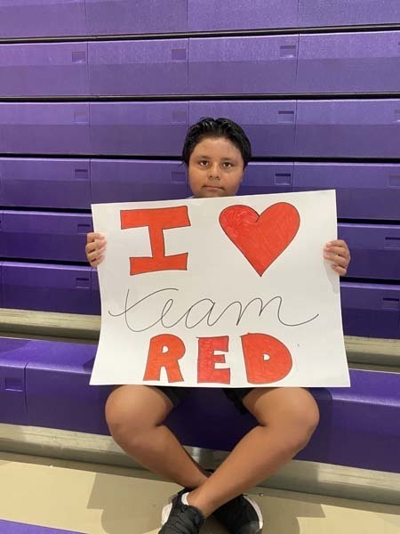 Student holding an I heart Team Red sign