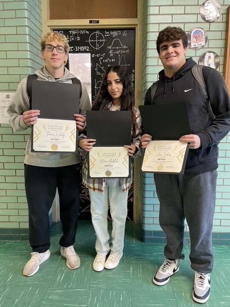 Students holding certificates and smiling at the camera