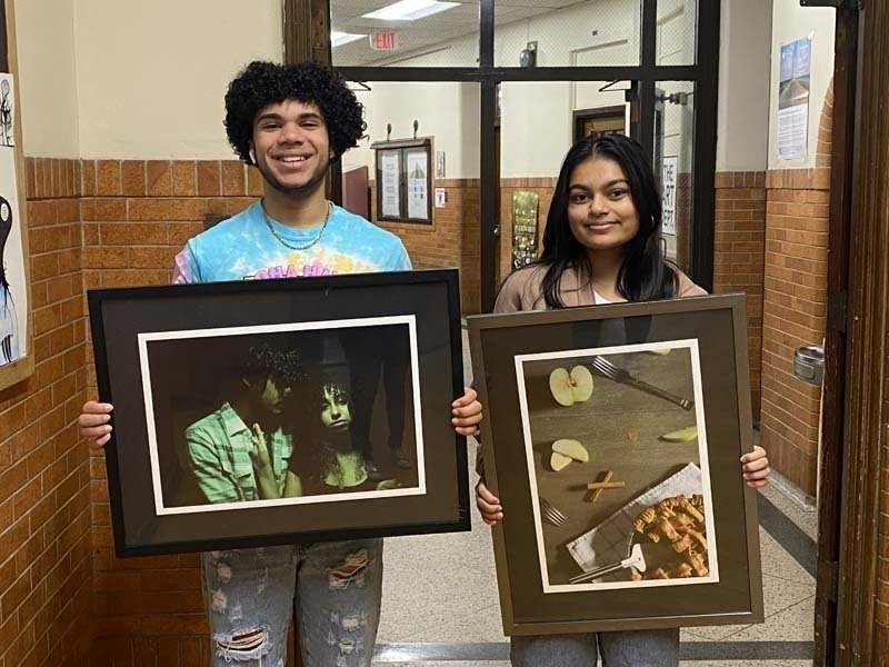 Two students holding up their artwork