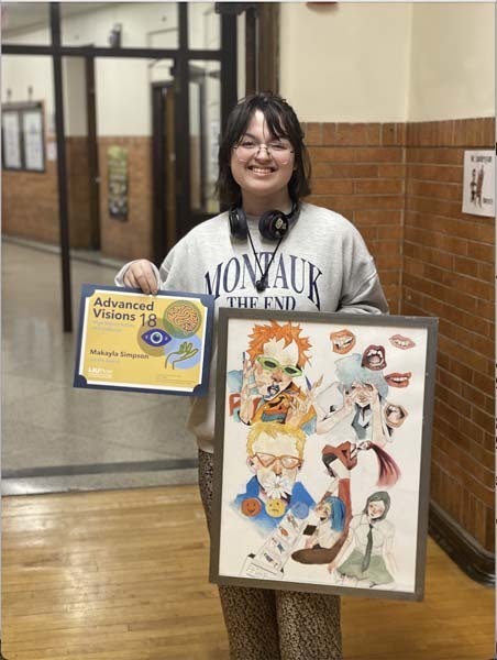 A student holding an award and artwork